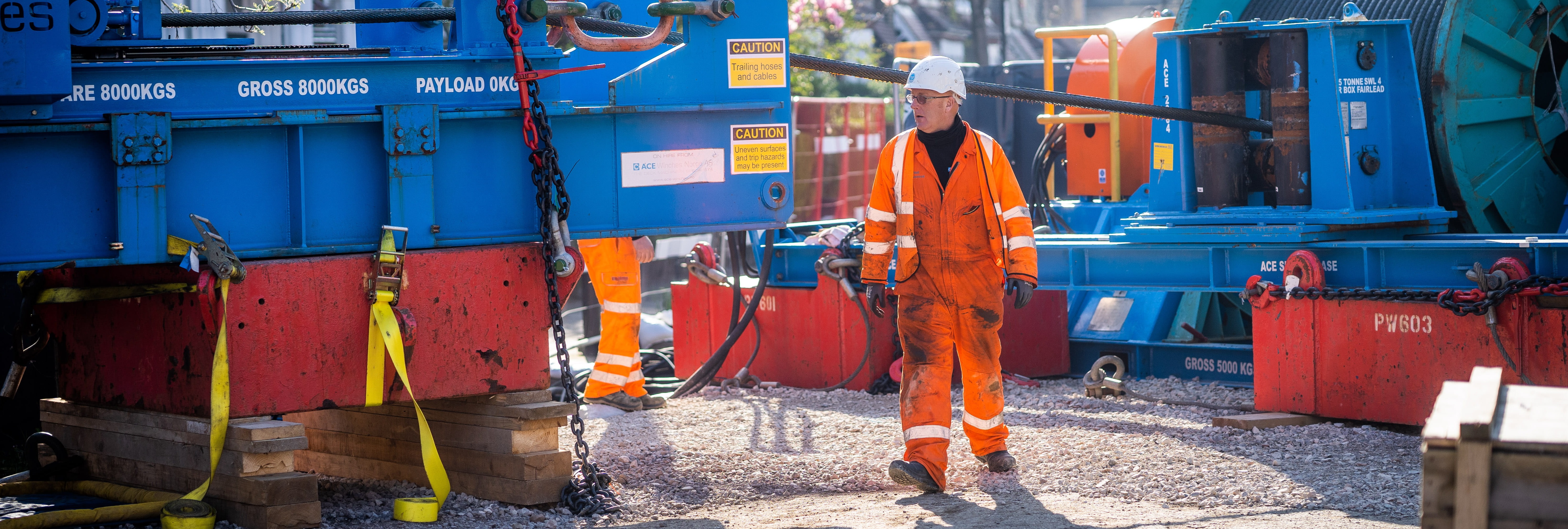 A man dressed in Thames Water work clothes walking next to machinery at a major works site
