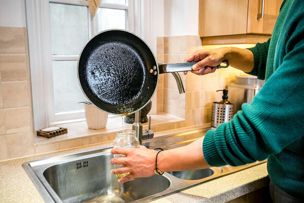 Pouring fats oils and grease into a container for disposal