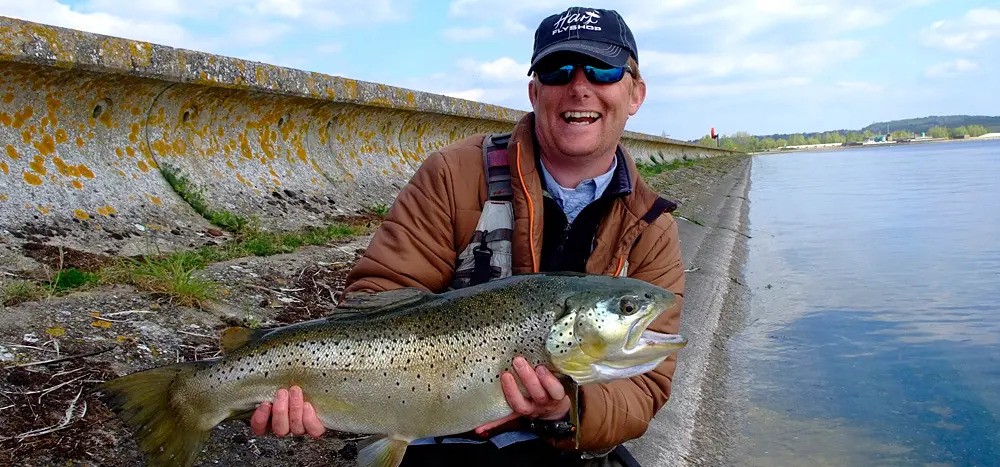 Image of a man smiling holding a freshly-caught fish