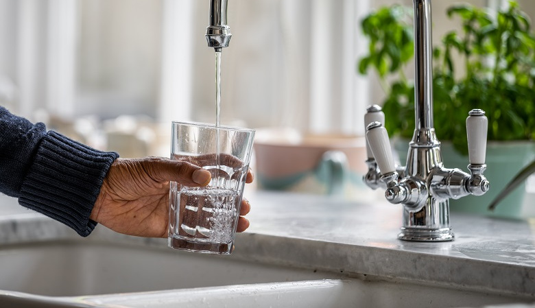 Someone pouring a glass of water from the kitchen tap